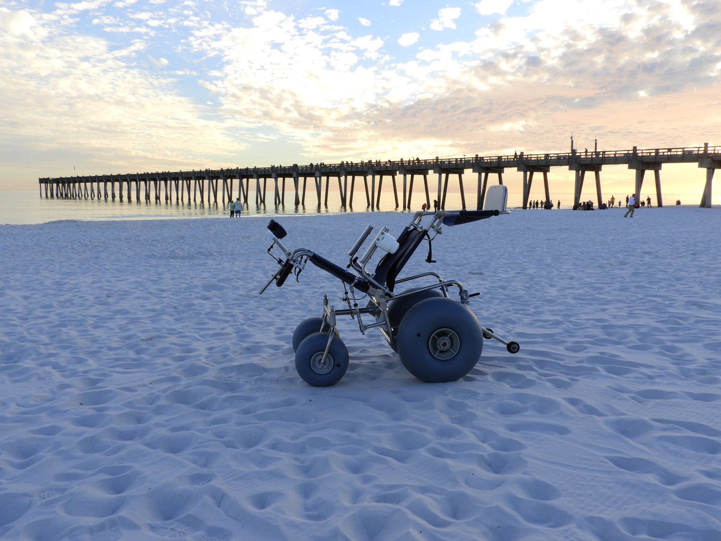 tilt in space beach wheelchair tilted back while sitting in the sand on the beach. No one is in the chair.