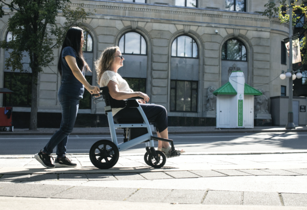 Triumph Prestige Rollator sky blue women being pushed on the sidewalk