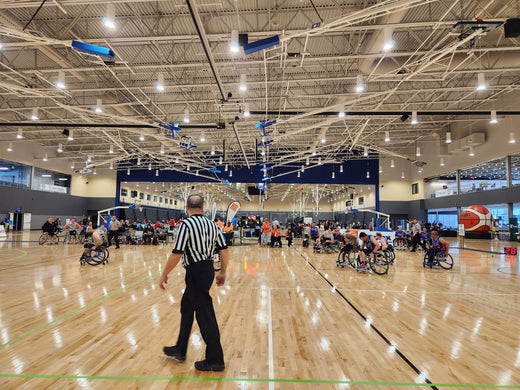 Wheelchair Basketball game with ref walking by.