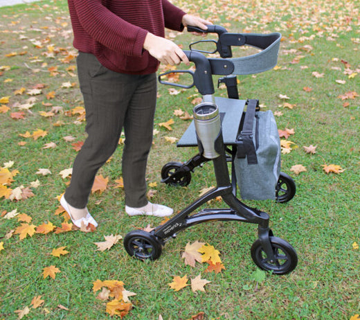 Rollator with woman using it in the grass.