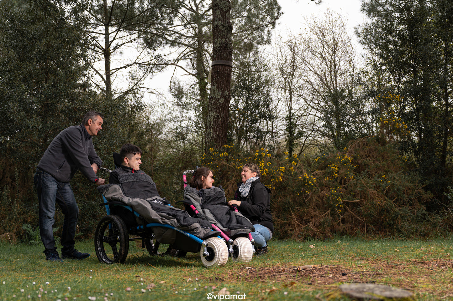 Beach and All-terrain Hippocampe Chair blue and pink in the woods with people and their family members