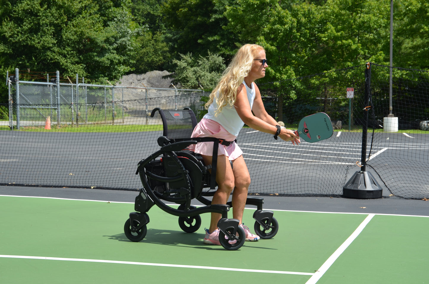 Woman playing pickleball on a court with a wheelchair