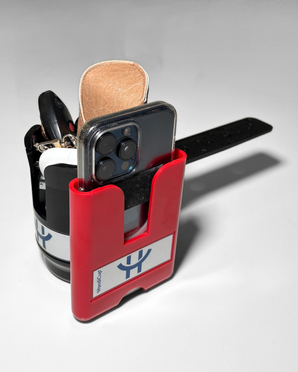 Phone holder attached to the wheelchair cup holder in the color red with keys and a phone